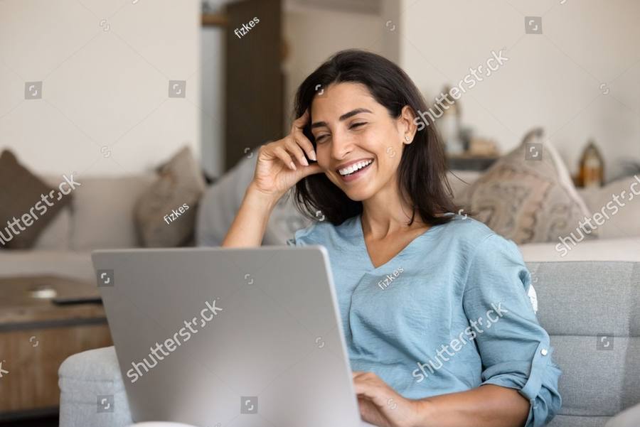 A woman laughing on a video call from her couch